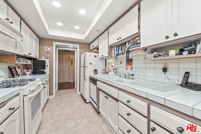 kitchen with white cabinetry, white appliances, tile counters, and sink