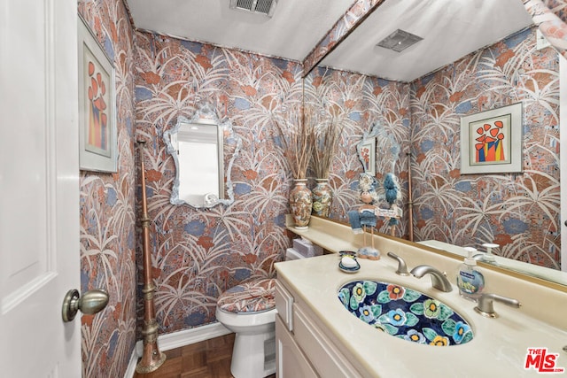 bathroom featuring vanity, parquet flooring, a textured ceiling, and toilet