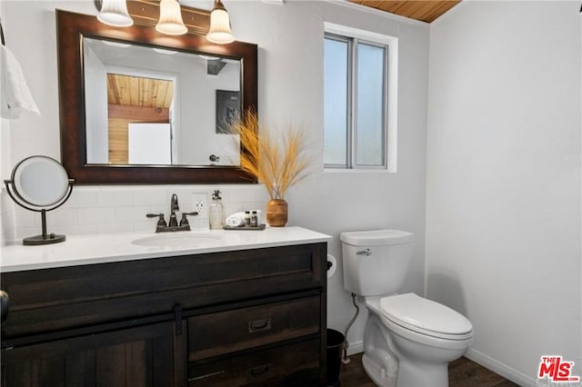 bathroom with toilet, a wealth of natural light, vanity, and decorative backsplash