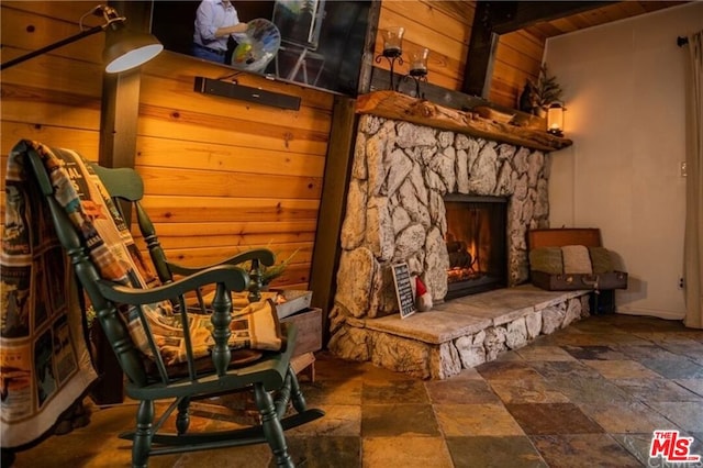 sitting room featuring a fireplace, wooden walls, and wooden ceiling