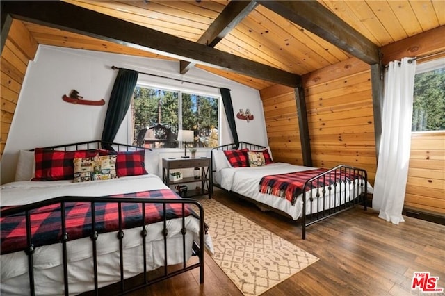 bedroom with multiple windows, hardwood / wood-style flooring, wooden walls, and lofted ceiling with beams