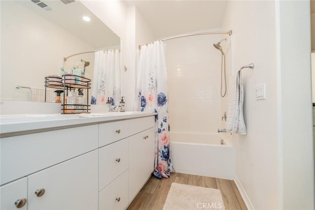 bathroom featuring wood-type flooring, shower / bathtub combination with curtain, and vanity