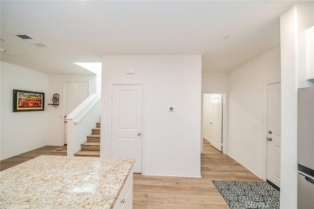 interior space featuring stainless steel refrigerator, light stone countertops, and light hardwood / wood-style floors