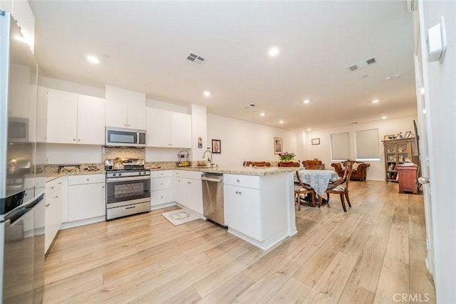 kitchen with white cabinetry, light hardwood / wood-style flooring, stainless steel appliances, and kitchen peninsula