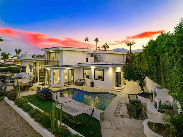 back house at dusk with outdoor lounge area and a patio area