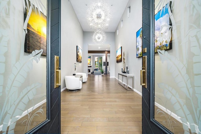 corridor with hardwood / wood-style flooring, a chandelier, and french doors