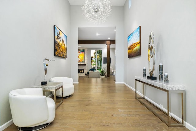 hallway featuring a towering ceiling, an inviting chandelier, and light wood-type flooring