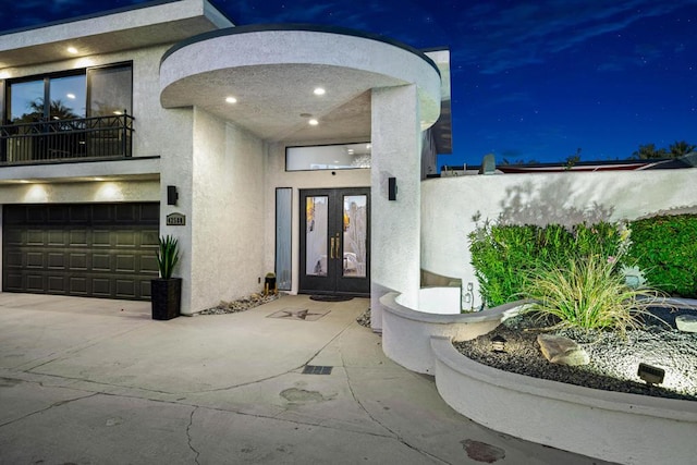 exterior entry at night featuring french doors and a garage