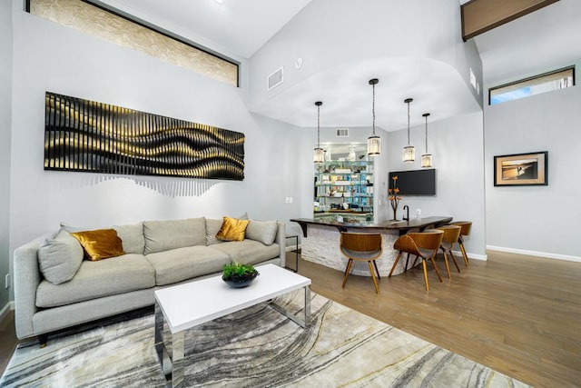 living room featuring hardwood / wood-style floors, a towering ceiling, and indoor bar