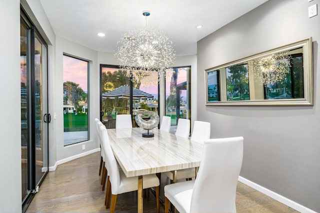 dining space with hardwood / wood-style flooring and an inviting chandelier