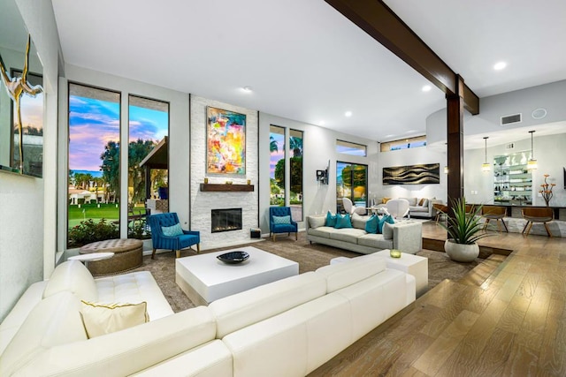 living room with beamed ceiling, a fireplace, and hardwood / wood-style floors