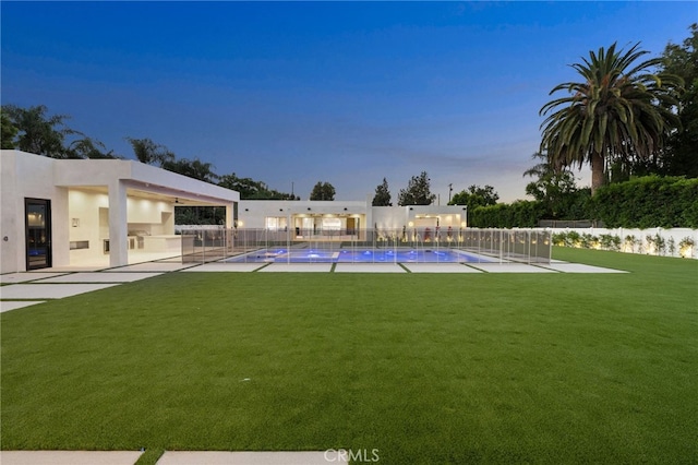 pool at dusk featuring a yard and a patio area