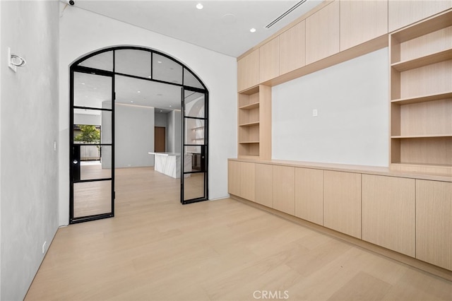 empty room with light hardwood / wood-style floors and built in shelves