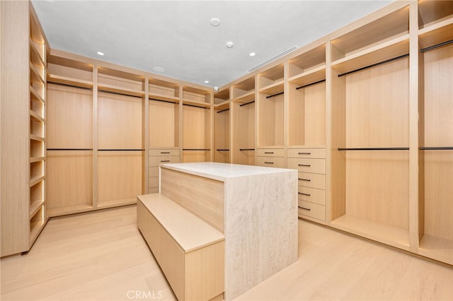 walk in closet with light hardwood / wood-style flooring