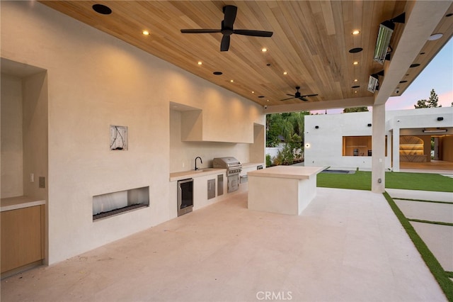 patio terrace at dusk featuring area for grilling, sink, and ceiling fan