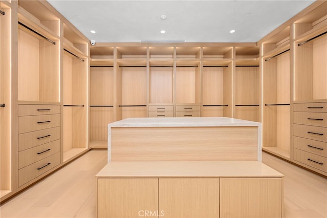 walk in closet with light hardwood / wood-style floors