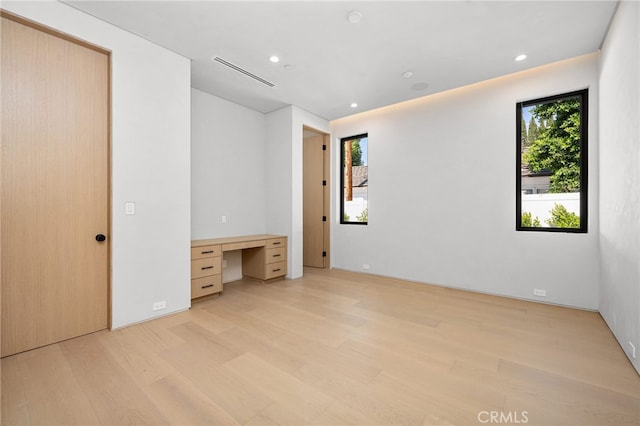 unfurnished bedroom featuring light hardwood / wood-style flooring and built in desk