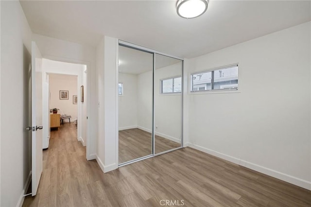 unfurnished bedroom with light hardwood / wood-style floors and a closet