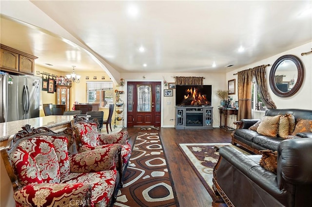 living room with a healthy amount of sunlight, dark hardwood / wood-style floors, and a chandelier