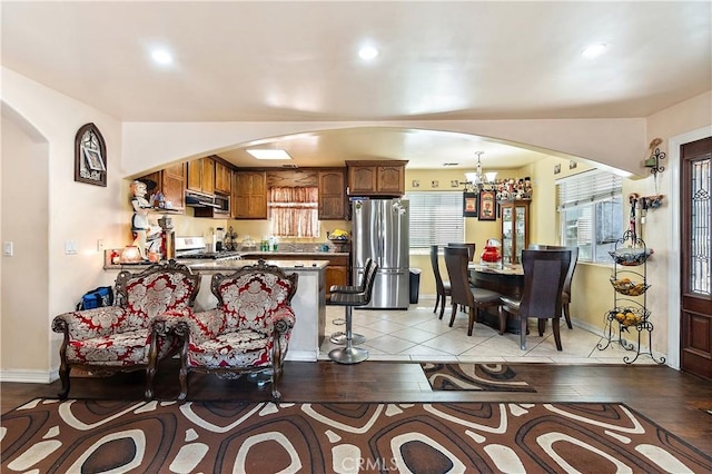 interior space featuring appliances with stainless steel finishes, a kitchen bar, kitchen peninsula, and light hardwood / wood-style floors