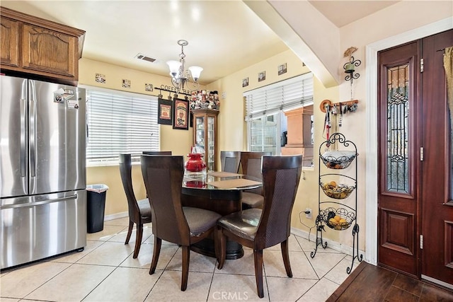 tiled dining room with an inviting chandelier