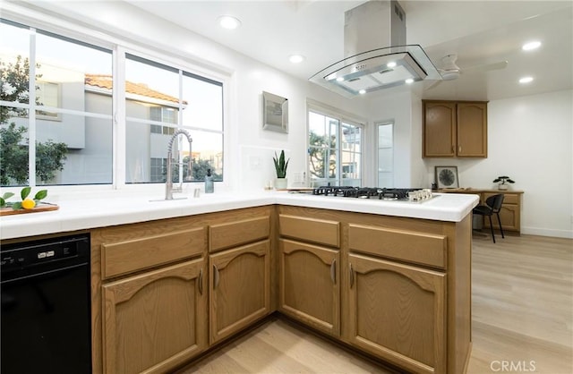 kitchen featuring island range hood, dishwasher, light hardwood / wood-style floors, kitchen peninsula, and gas stovetop