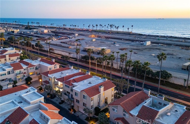 aerial view at dusk with a water view and a beach view