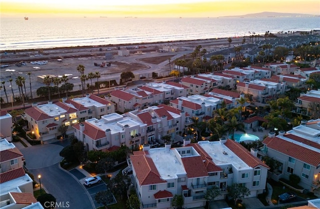 aerial view at dusk with a view of the beach and a water view