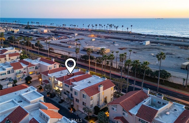 aerial view at dusk featuring a view of the beach and a water view