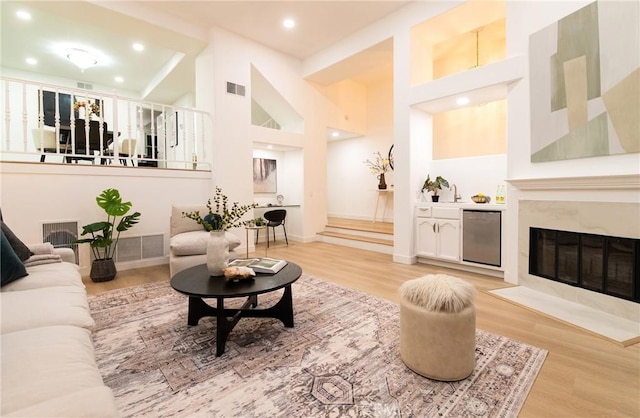 interior space with a tile fireplace, a towering ceiling, and light hardwood / wood-style floors