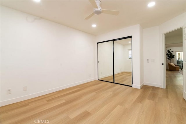 unfurnished bedroom featuring ceiling fan, a closet, and light hardwood / wood-style flooring