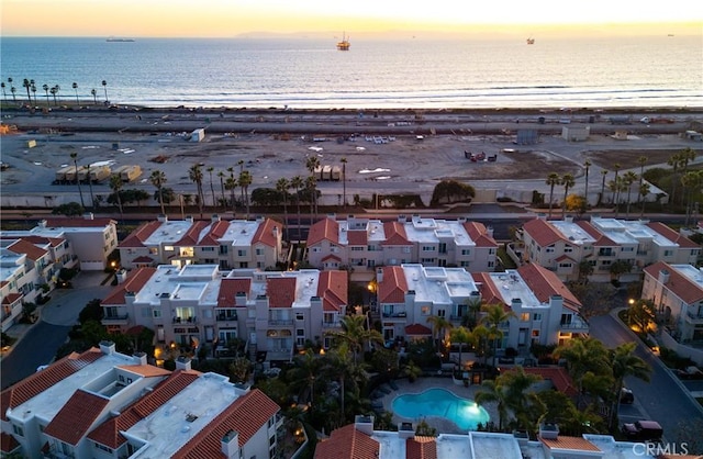 aerial view at dusk with a view of the beach and a water view