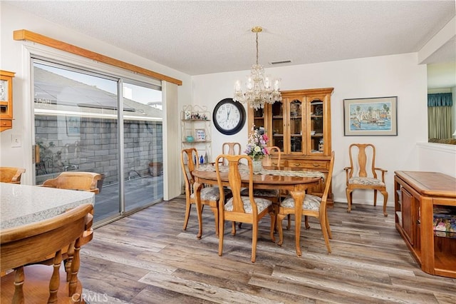 dining space with hardwood / wood-style floors, a chandelier, and a textured ceiling