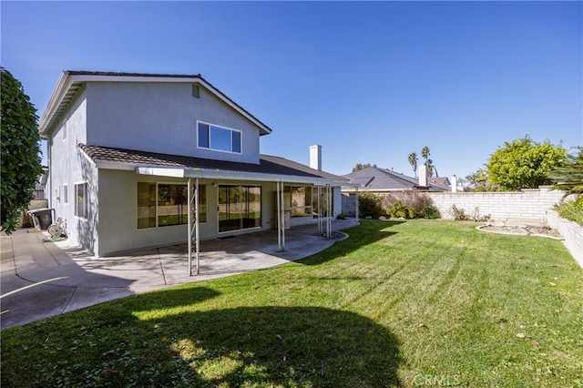 back of house with a patio area and a lawn