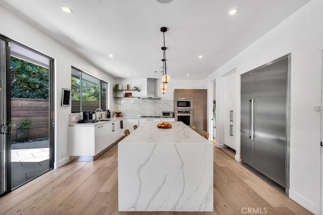 kitchen featuring light stone counters, built in appliances, a kitchen island, pendant lighting, and white cabinets