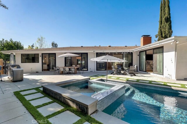 rear view of property with a bar, a pool with hot tub, and a patio area