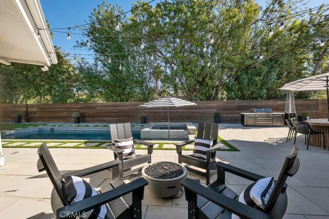 view of patio featuring exterior bar, a pool with hot tub, grilling area, and a fire pit