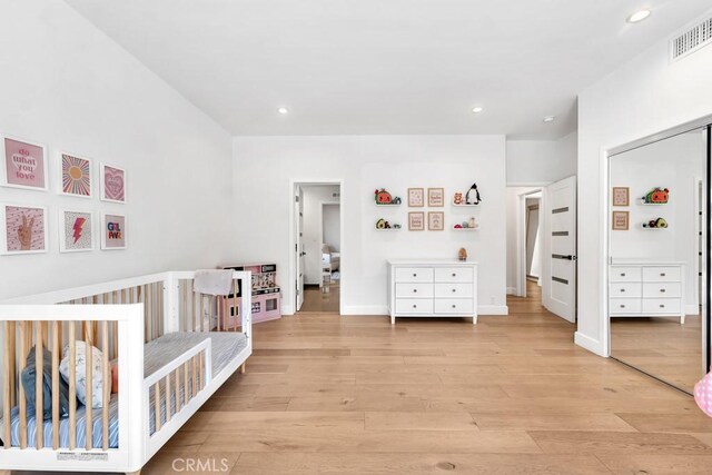 bedroom with a nursery area and light wood-type flooring