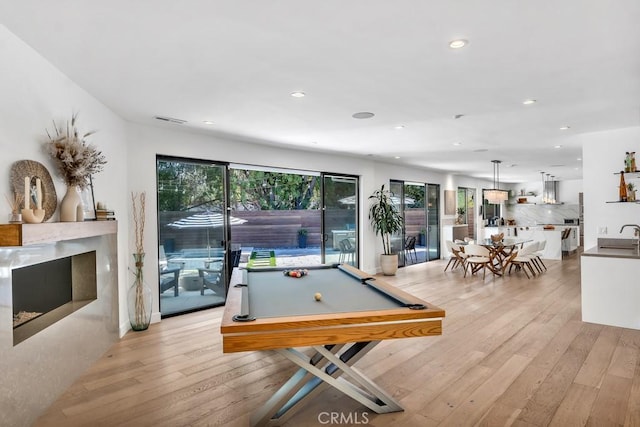 game room with pool table, sink, and light hardwood / wood-style floors