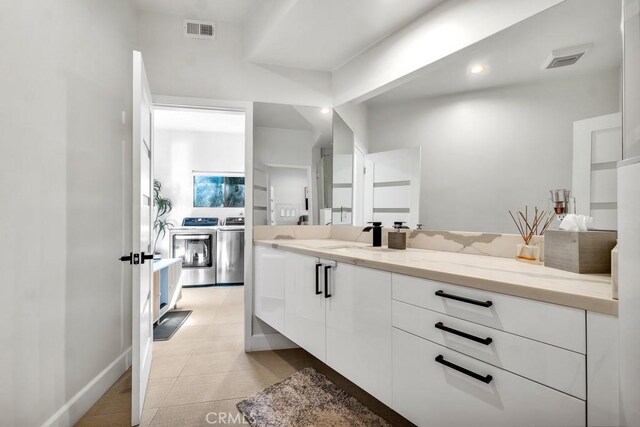 bathroom with tile patterned flooring, washing machine and dryer, and vanity