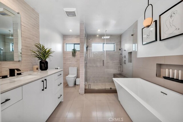 full bathroom with tile walls, tile patterned flooring, vanity, separate shower and tub, and toilet