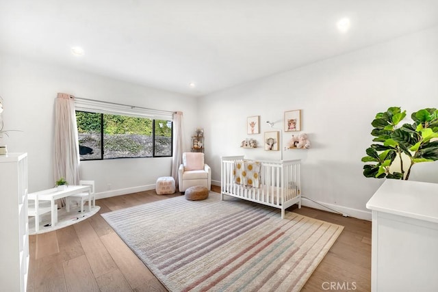 bedroom with a crib and light hardwood / wood-style flooring