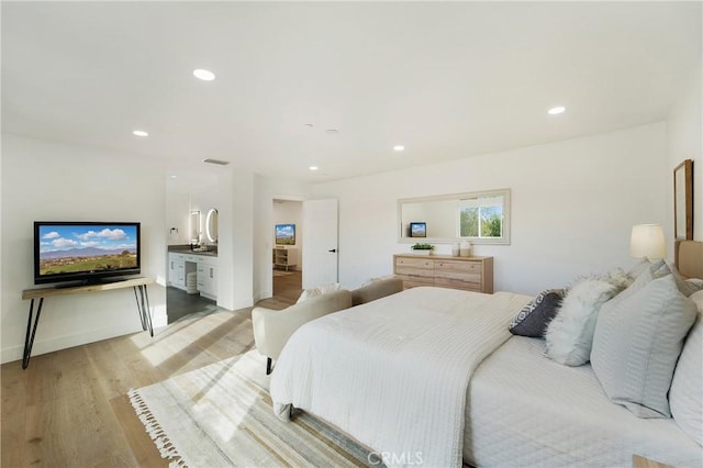 bedroom featuring light wood-type flooring and ensuite bath