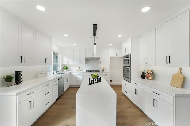 kitchen with white cabinetry, appliances with stainless steel finishes, a center island, and hardwood / wood-style floors