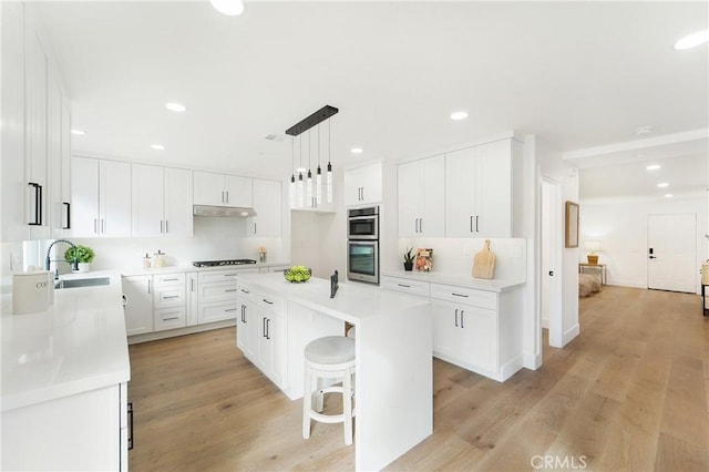 kitchen with white cabinetry, a center island, a breakfast bar, and decorative light fixtures