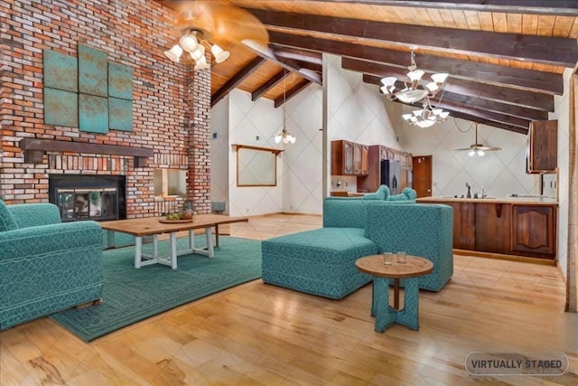 living room featuring ceiling fan with notable chandelier, high vaulted ceiling, a fireplace, beamed ceiling, and wooden ceiling