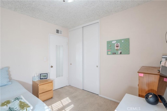 bedroom featuring light colored carpet, a closet, and a textured ceiling