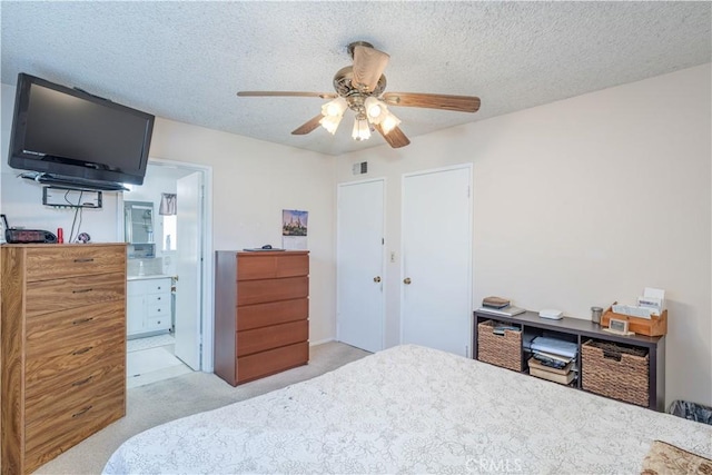 carpeted bedroom with ceiling fan, ensuite bath, and a textured ceiling