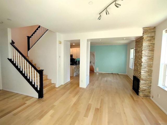 unfurnished living room featuring light hardwood / wood-style floors, rail lighting, and a healthy amount of sunlight