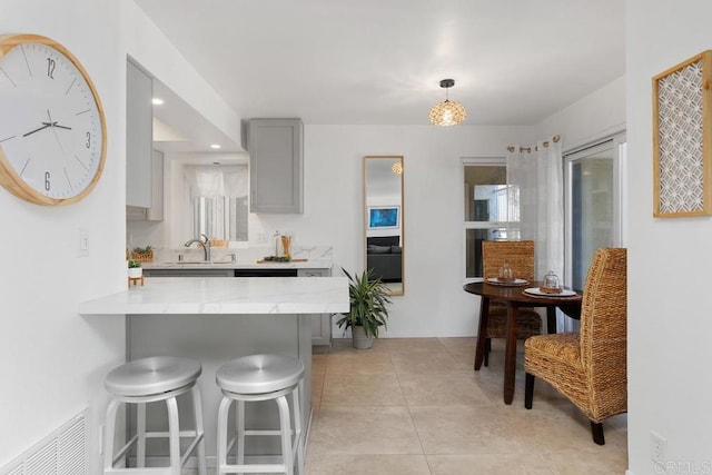 kitchen featuring sink, hanging light fixtures, a kitchen breakfast bar, gray cabinets, and kitchen peninsula